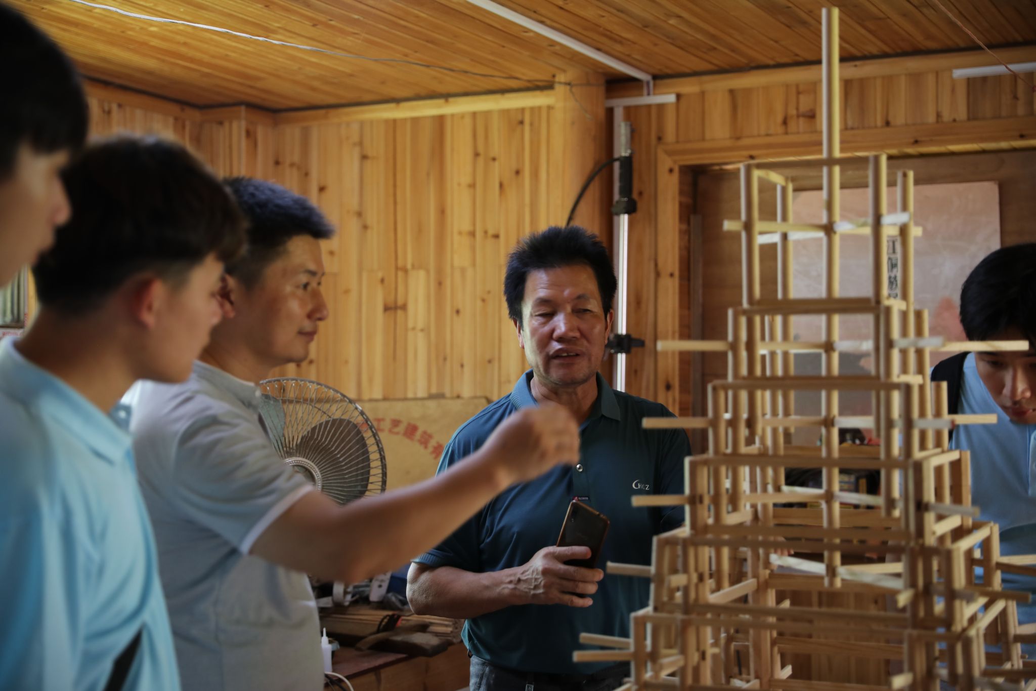 楊似玉大師利用鼓樓模型向?qū)嵺`團(tuán)成員解說(shuō)鼓樓建筑結(jié)構(gòu)